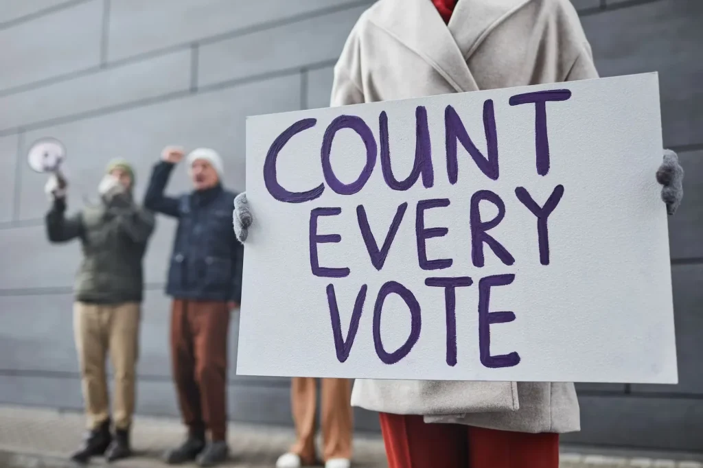 Protesters holding signs and chanting for fair vote count during a winter rally.